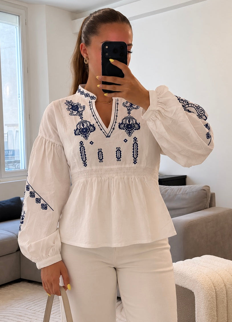 Blouse Hortense blanche à broderies bleues, manches bouffantes, taille smockée et col en V, style bohème chic pour femme.