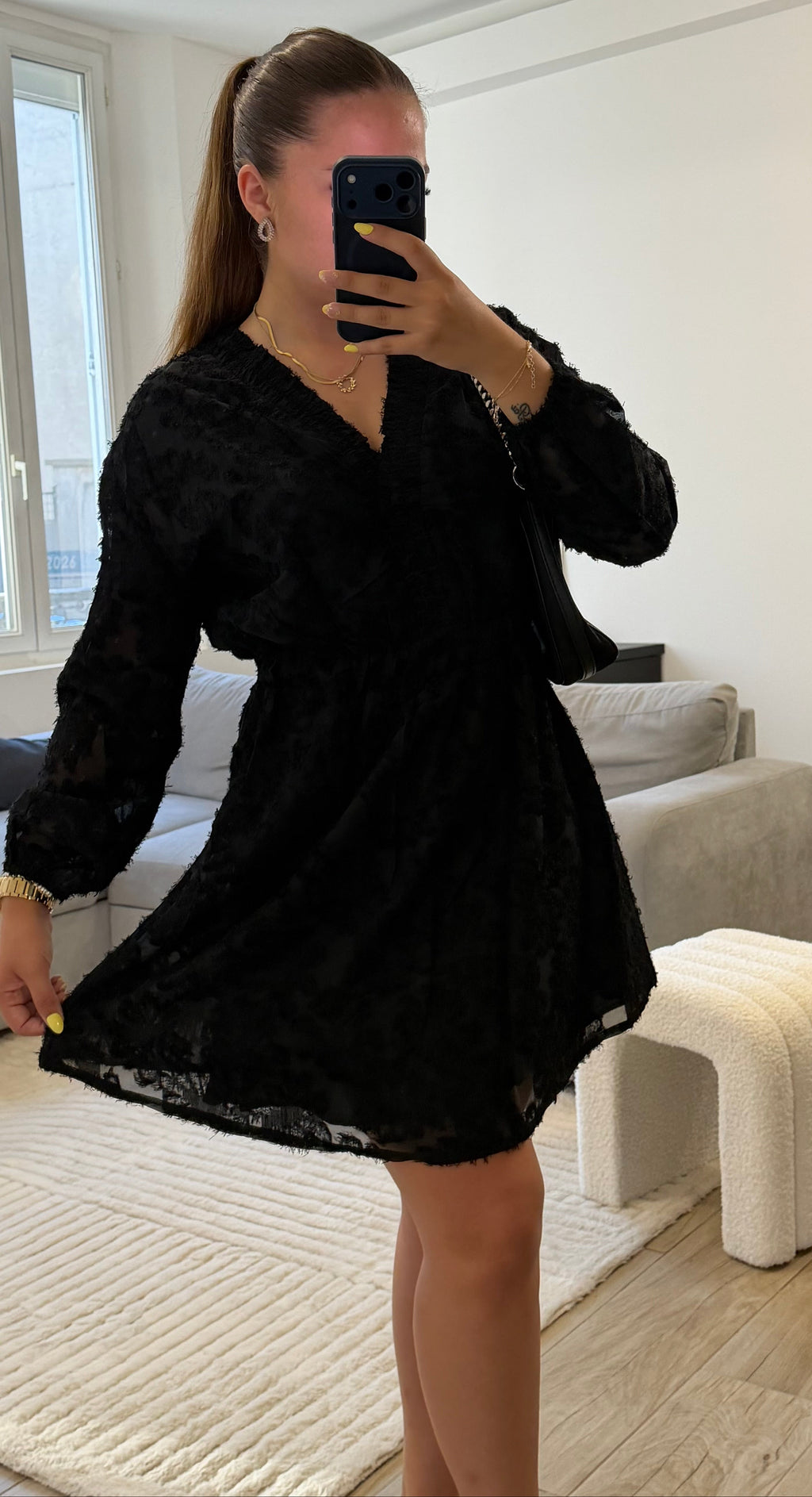 Robe Victoria noire à manches longues, col en V, tissu texturé ton sur ton et coupe courte évasée, style chic pour femme.