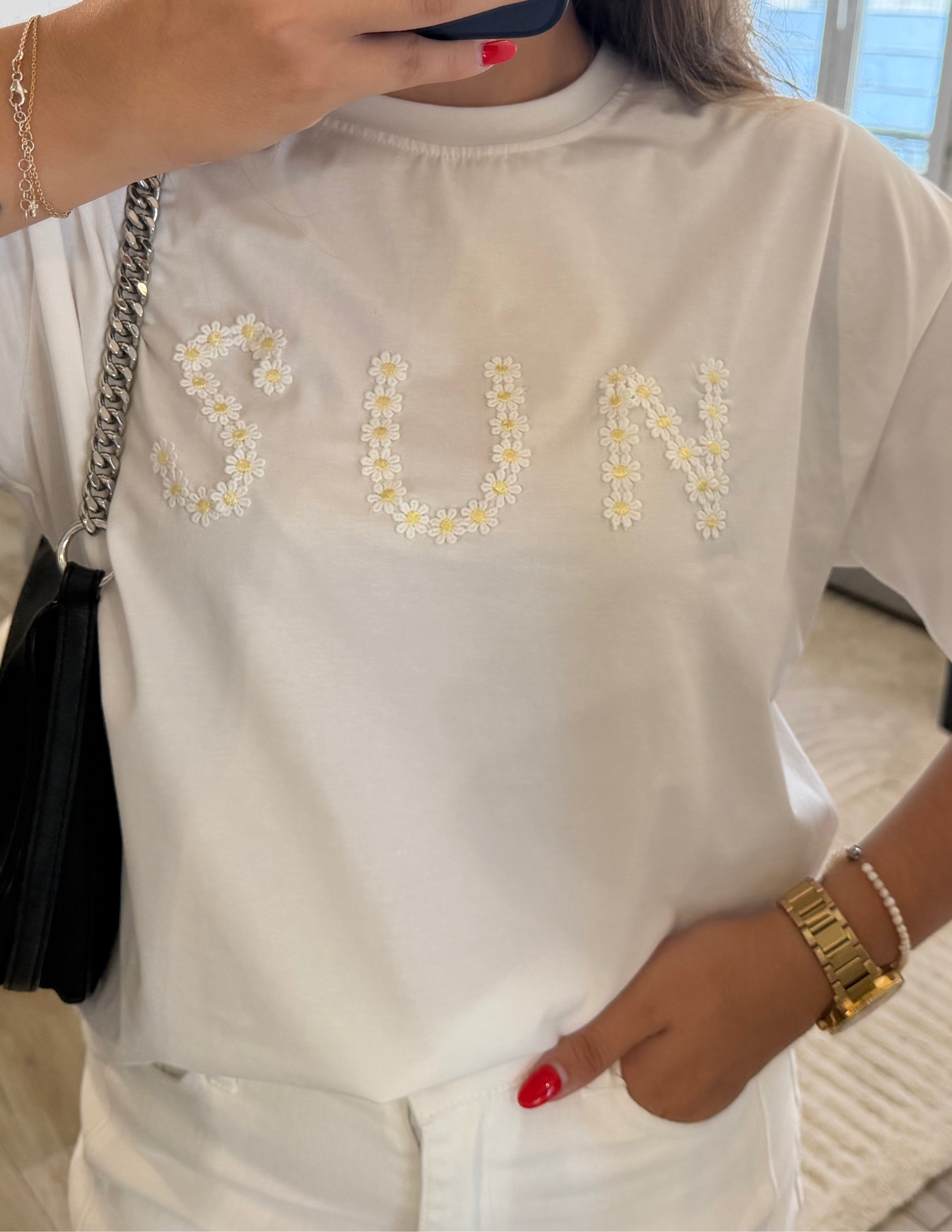 Détail des fleurs brodées formant l'inscription « SUN » sur le T-shirt Alba.